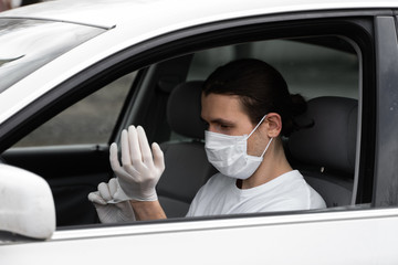 Fototapeta na wymiar Man in protective medical mask is wearing rubber gloves for protect himself from bacteria virus while planning to drive. Protective mask while quarantine, pandemic, covid 19, coronavirus, infection.