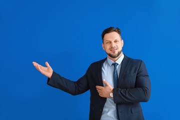 Stylish businessman showing something on color background
