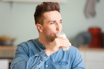 Young man drinking milk in kitchen