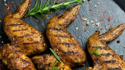 grilled chicken wings with red sauce on a black stone surface