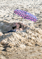 Man relaxing in a cool hole dug in the sand