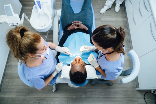 Female dentist and assistent attending patient in medical practice