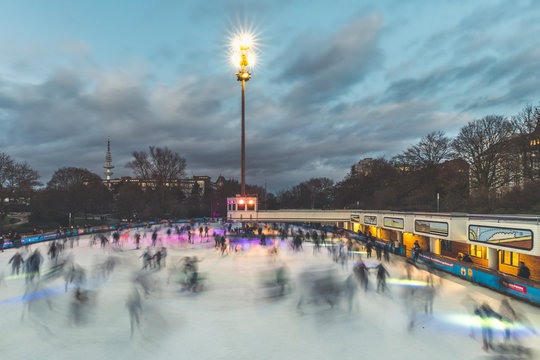Germany, Hamburg, People ice-skating in Planten un Blomen park at dusk