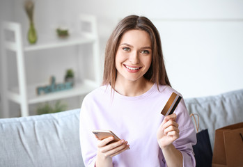 Young woman with mobile phone and credit card at home. Online shopping concept