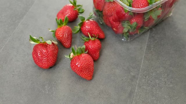 1 kg fresh strawberries in plastic box, on gray wooden background