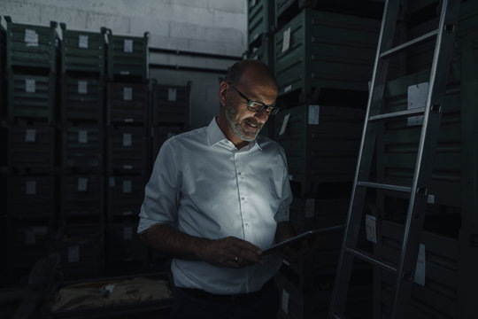 Businessman using tablet in a factory in the dark