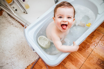 Portrait of baby boy in bathtub sticking out tongue