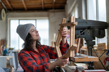 Carpenter holding workpiece in her workshop