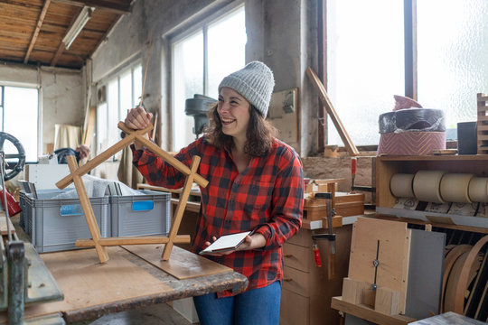 Happy carpenter holding workpiece in her workshop