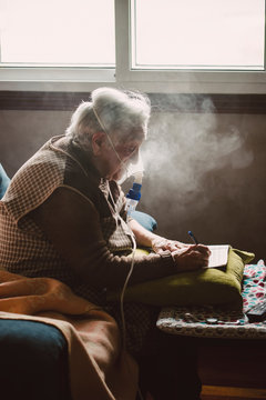 Senior woman using inhaler at home