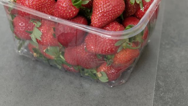 1 kg fresh strawberries in plastic box, on gray wooden background