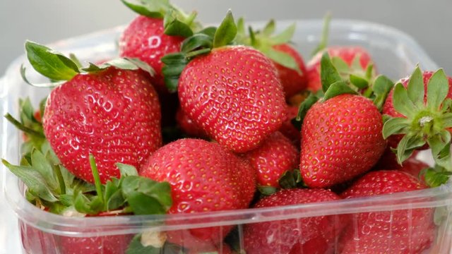 1 kg fresh strawberries in plastic box, on gray wooden background