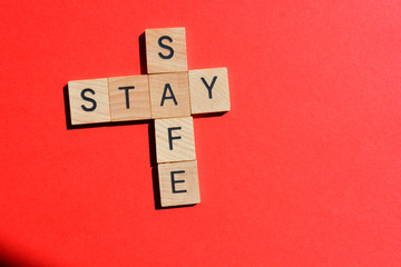 Stay Safe, words in 3d wooden alphabet letters on red background