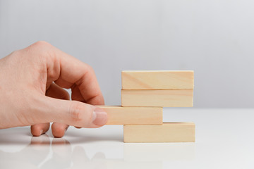 Concept of wrong actions in business.. Hand holds wooden blocks on a white background.