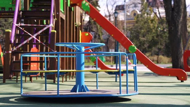 Abandoned carousel and slides with restriction tape on empty playground