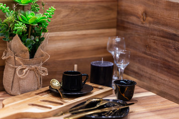 Coffee still life with cup of coffee. black vintage cups of black coffee on old wooden table. Still life with coffee, flowers and dishes of black color on the background of old wooden planks