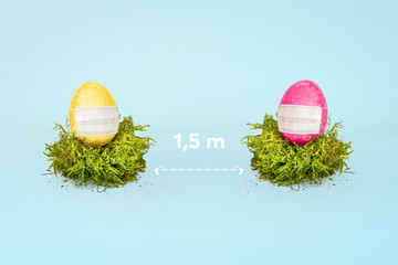 Ostereier im Nest mit Mundschutz vor blauem HIntergrund mit Raum für Copytext. Corona Virus (Covid-19). Social Distancing.