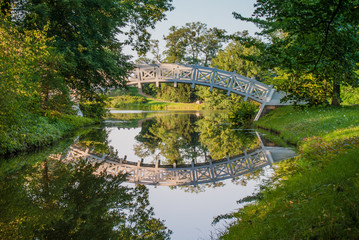 Fototapeta na wymiar White pedestrian bridge with reflection in the water, Unesco Park Dessau-Wörlitz, Germany