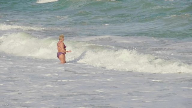 Woman in age swims in the sea in a swimsuit.