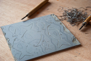 Etched linoleum with scraps and tools on table
