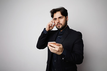Portrait of serious bearded businessman using smartphone in suit on the white background.
