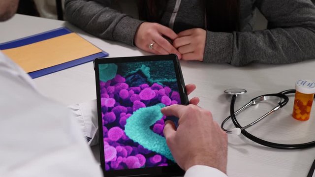 Medical Professional Doctor, using a tablet computer to explain the virus bacteria to his female patient. Public Domain Image