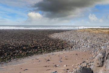 Rough stone beach and cloudy dramatic sky, Atlantic ocean, Wet and dry stone create S shape. Strandhill beach, county Sligo, Ireland.