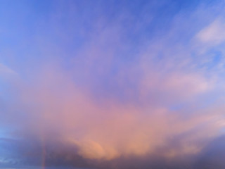 Fototapeta na wymiar Cloudy sky. Nature scenic background. Small rainbow on the left.