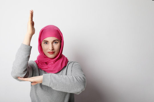 Close-up portrait of a muslim young woman wearing a hijab and putting hand up. Human rights concept.