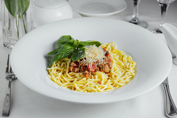 spaghetti bolognese on a white plate with wide fields on a serving table