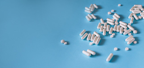 White medical pills on blue background. 
