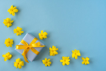 Gift with yellow flowers on blue background . Top view, flat lay 