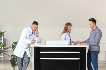 Female medical assistant with patient and doctor in clinic