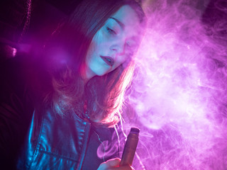 Girl with a vape device. Woman in a cloud of cigarette smoke. A