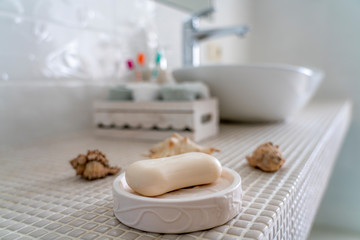 soap lies in a ceramic soap dish on the background of the washbasin in the bathroom