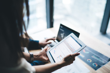 Woman showing charts on tablet to coworker