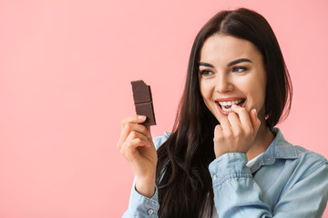 Beautiful young woman with chocolate on color background