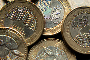 Naklejka premium Macro Photography to a pile of Colombian coins over black background. Ideal for economy, money, banks, save money and finance. 