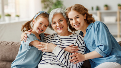 Senior woman with daughter and granddaughter on couch.