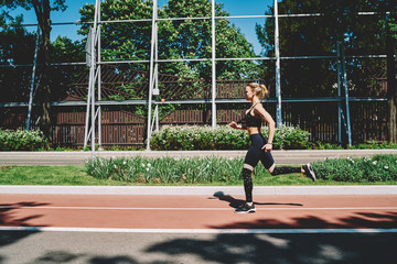 Athletic young sportswoman jogging on track in street