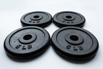 Closeup to a four dumbbell disc of 5 pounds over white background.  Ideal for fitness, sports, and healthy life. 