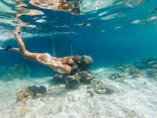 Young blonde snorkeling in sea near pier