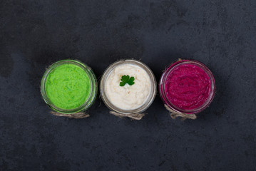 Obraz na płótnie Canvas Russian appetizer horseradish with beetroot, green horseradish wasabi, white horseradish with lemon and garlic in jars in a dark style top view