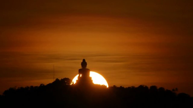 hue sunset behind silhouette Phuket big buddha statue on hilltop with many big trees high mountain in the beautiful evening colourful  orange twilight sky , attraction tourist photo spot
