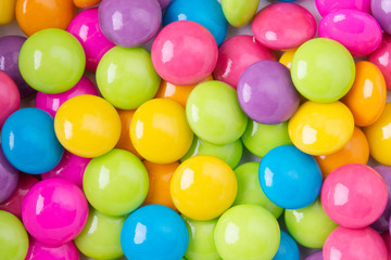 Pile of colorful sweet candy chocolates coated on white paper. colourful collection background.