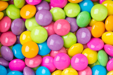 Pile of colorful sweet candy chocolates coated on white paper. colourful collection background.