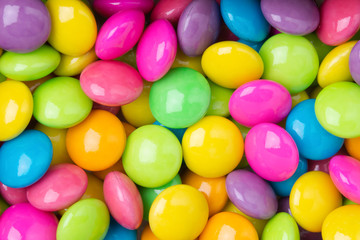 Pile of colorful sweet candy chocolates coated on white paper. colourful collection background.