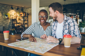 Laughing couple playing with map during organizing travel