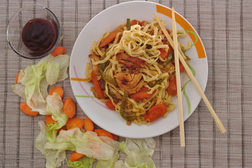 Top view of chinese food which include vegetables like carrots and lettuce with noodles, chicken and soya sauce.