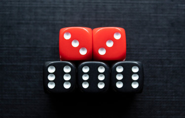 Closeup to a black and red dices. three black dices and two red dices over black background. Ideal for gamble, board games and bets